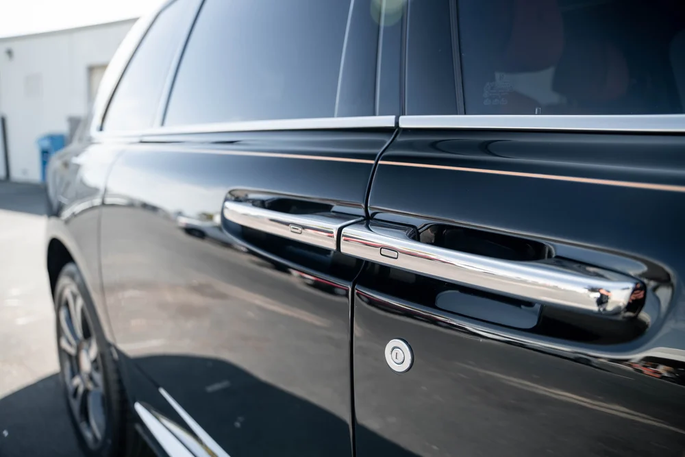 Black Rolls-Royce Cullinan with Chrome Exterior Trim — paired bright door handles, dark side glass and reflective black door panels