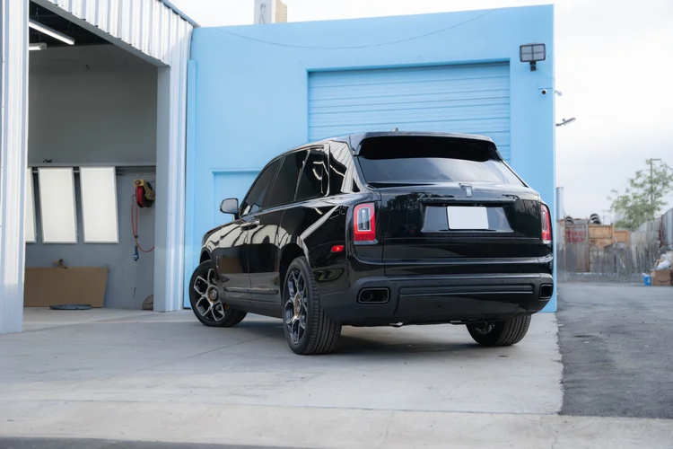 Black SUV shown from the rear corner beside the blue garage door.