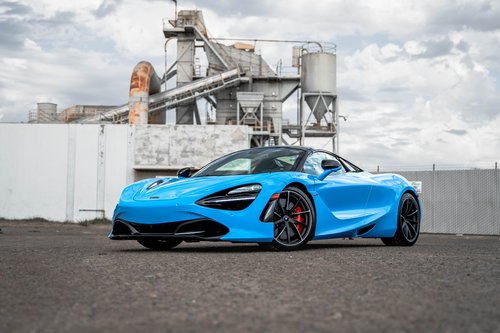 Blue McLaren 720S in a full front three-quarter view with dark aero trim, black wheels and red brake calipers