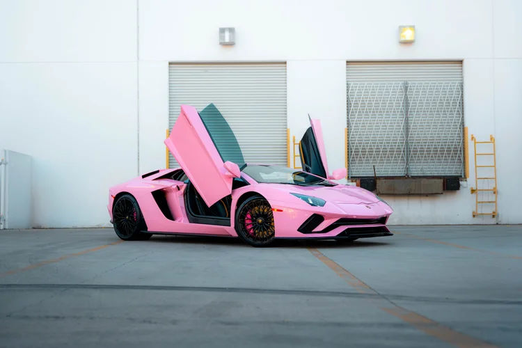 Sakura Pink Lamborghini Aventador in a complete front three-quarter view with both scissor doors raised and black wheels.