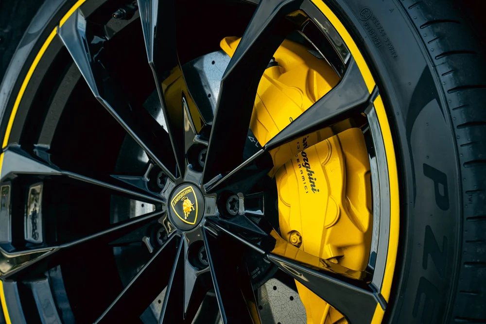 Lamborghini Urus with Chalk vinyl wrap, dark wheel spokes, yellow rim accent and yellow Lamborghini caliper close-up