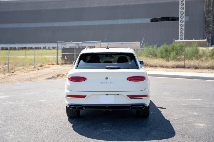 Complete rear view of the white SUV with its shadow extending across the pavement.