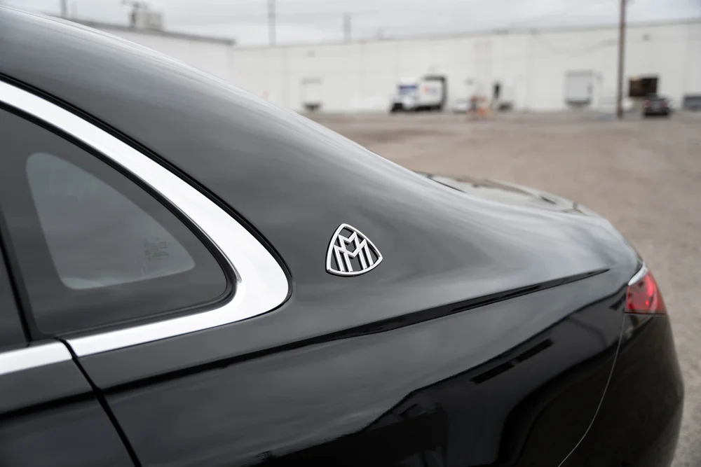 Bright Maybach emblem on the black rear pillar beside a triangular window and bright window surround