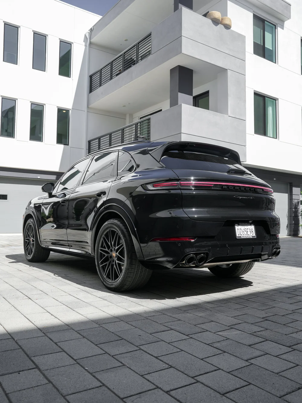 Complete rear three-quarter view of the black Cayenne GTS showing its side, rear bumper, wheels, roof spoiler and quad exhaust tips.