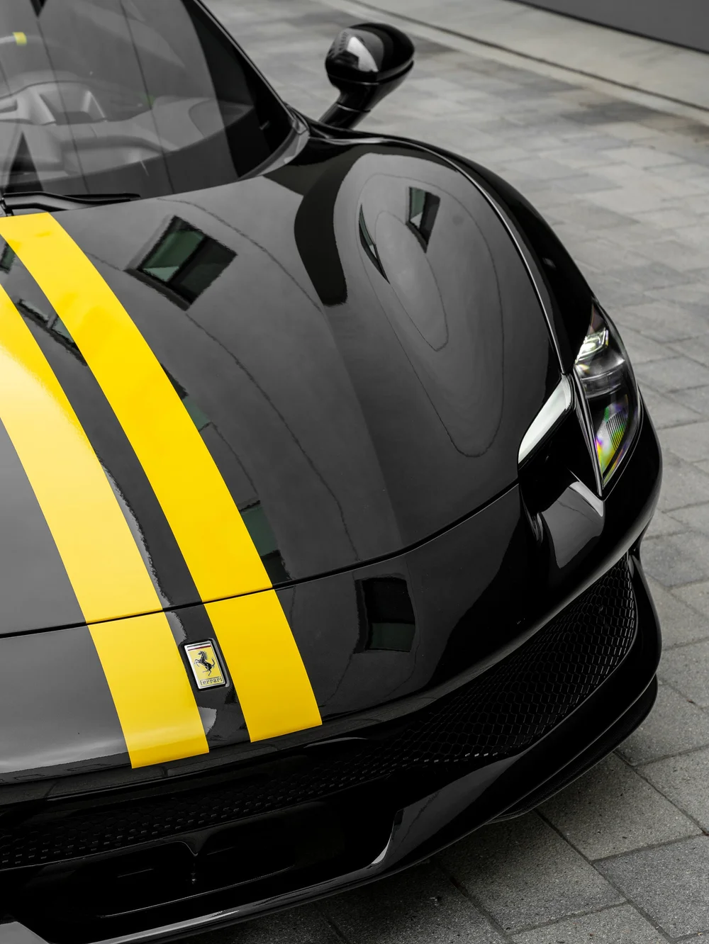 Angled hood detail of the Ferrari 296 GTB with two yellow stripes and the Ferrari badge