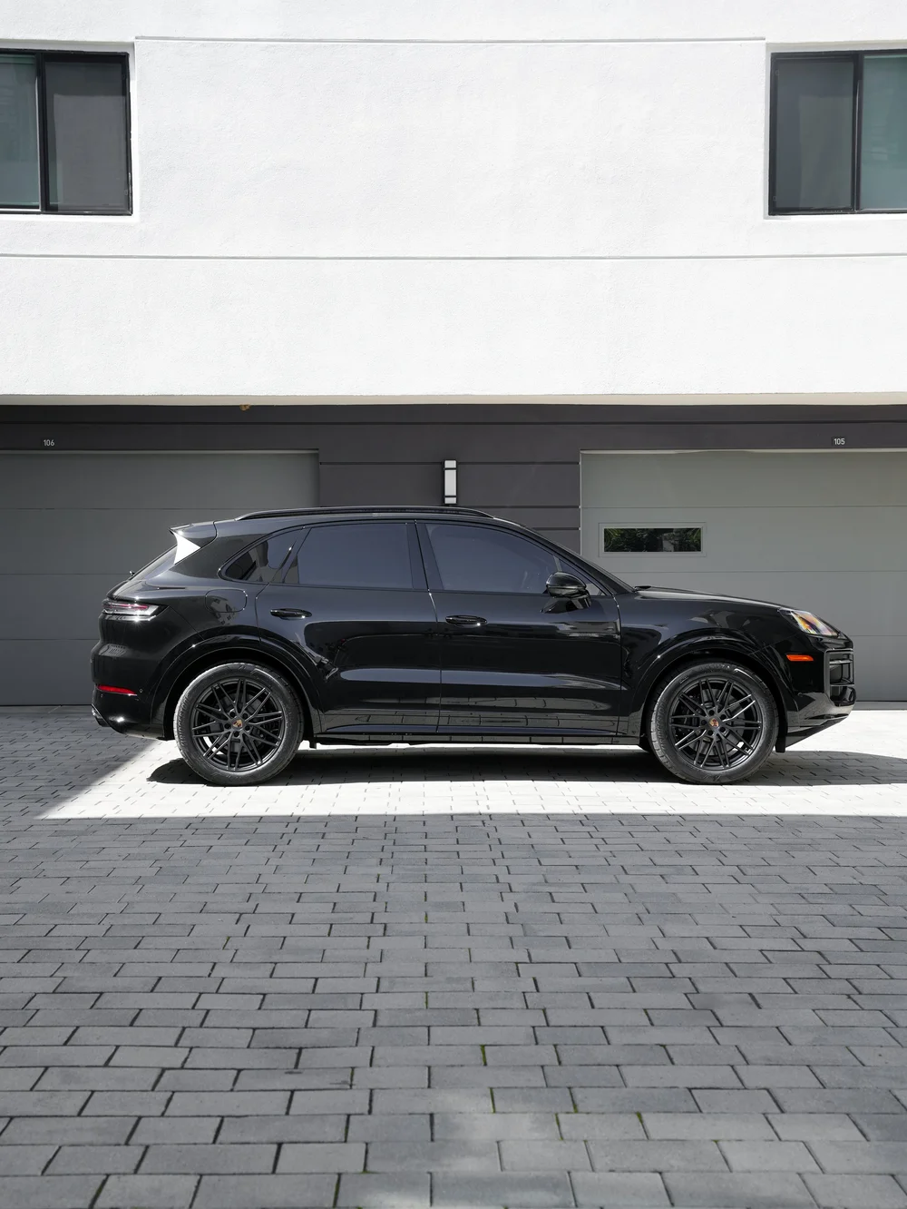 Complete side profile of the black Cayenne GTS with both visible wheels, roof rails, mirror and body ends on paving.