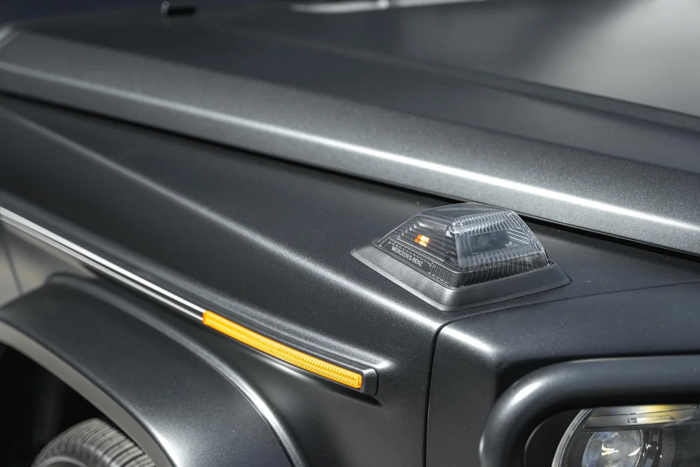 Close view of the G 550 clear fender-top lamp and amber side reflector beside matte-looking grey hood and fender contours