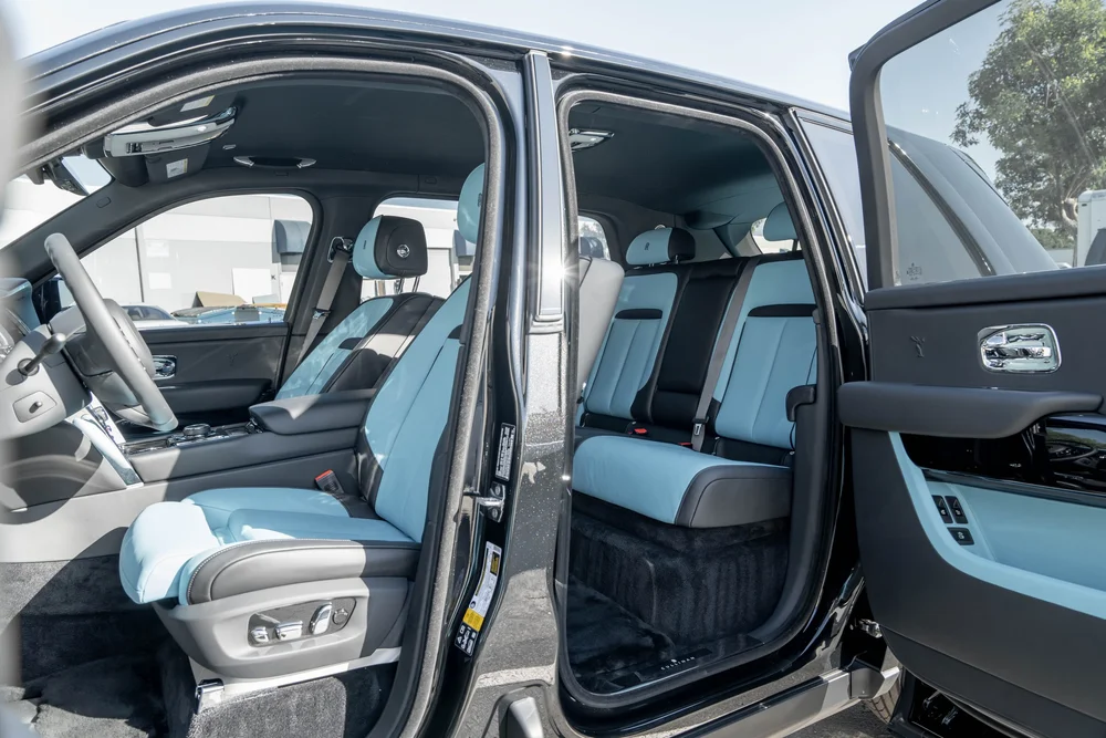 Dark Metallic Grey Rolls-Royce Cullinan — pale-blue cabin upholstery shown through both open side doors