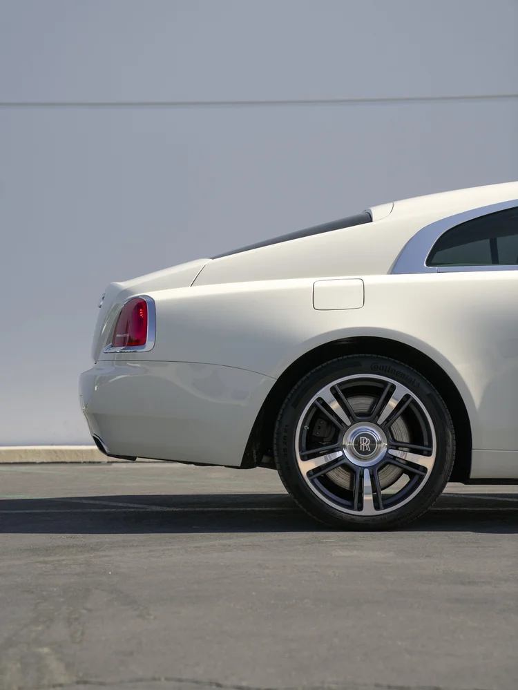 Pale Rolls-Royce Wraith rear quarter with a silver wheel, red taillamp and closed body flap.