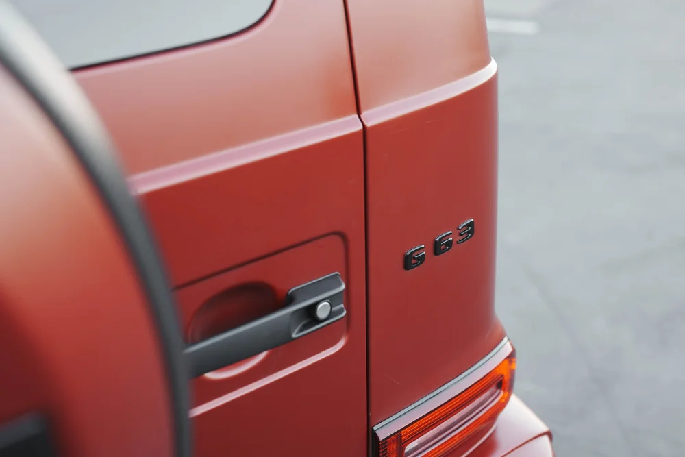 G63 lettering beside the black rear door handle and rear lamp on the matte red body