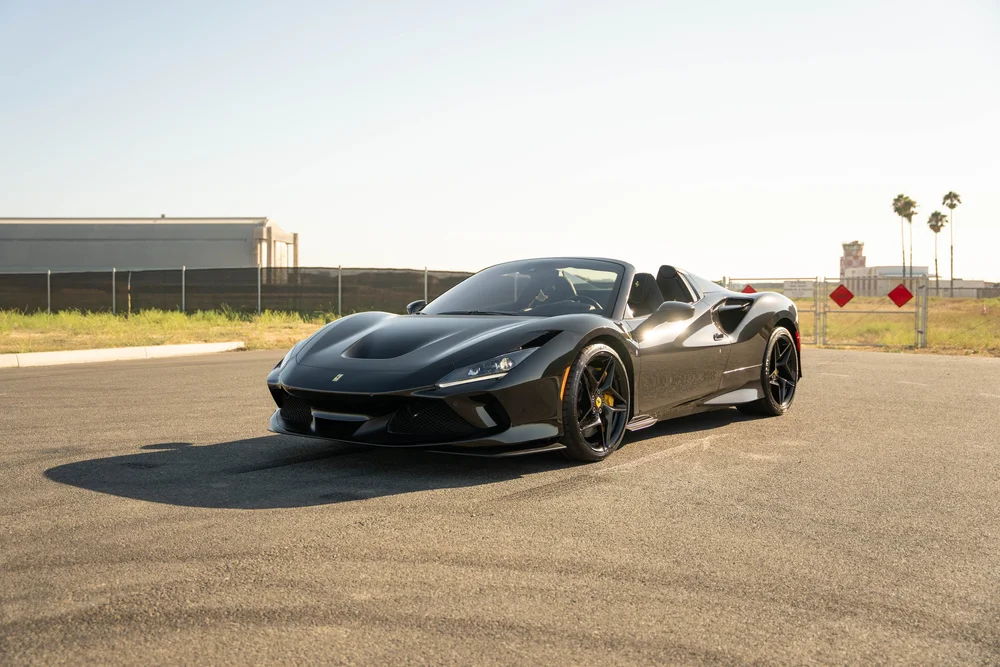 Complete front three-quarter view of the black Ferrari F8 showing both wheels, open cockpit and side intake