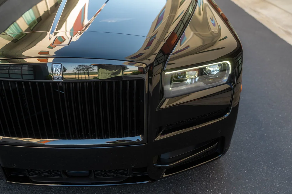 Black Rolls-Royce Cullinan Black Badge with Two-Tone Wheels — elevated front detail showing the hood, grille and headlamp area