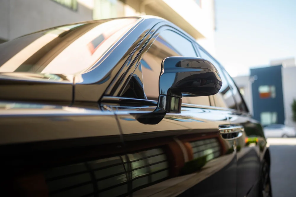 Black Rolls-Royce Cullinan Black Badge with Two-Tone Wheels — side mirror, glass and black exterior-panel reflections