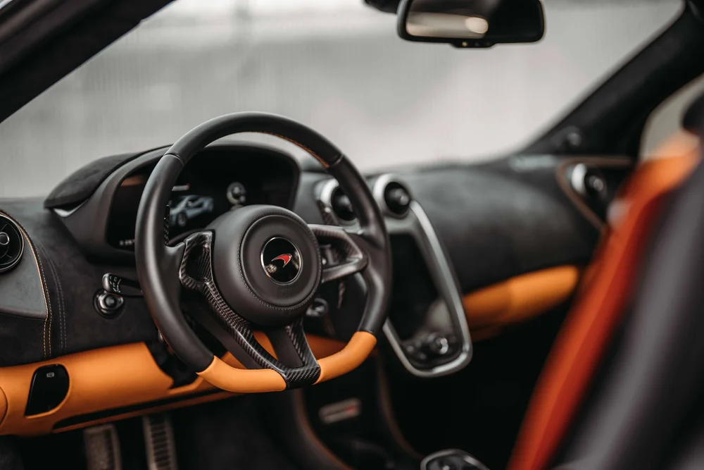 Dark cabin with orange dashboard and steering-wheel accents around the tall center console.