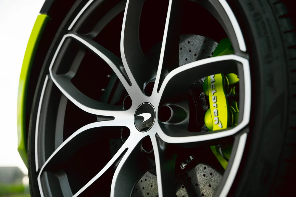 McLaren wheel with black-and-silver spokes, a green brake caliper and drilled brake disc