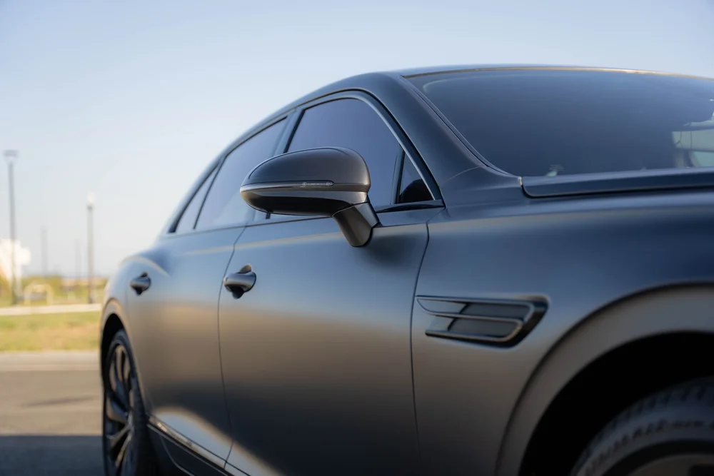 Side-glass and door detail with the mirror above the black fender vent.