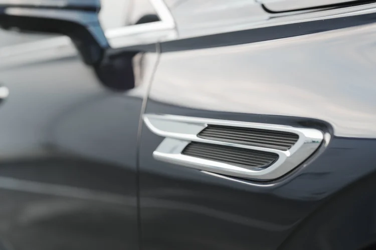 Silver-edged fender vent reflected across the dark body panel.