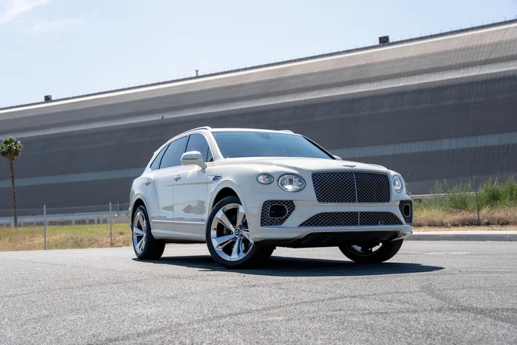 White Bentayga photographed from the front corner with round lamps and a mesh grille.