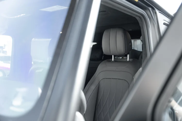 Grey seat and headrest viewed through the open side window of the G 550 beside dark window frames