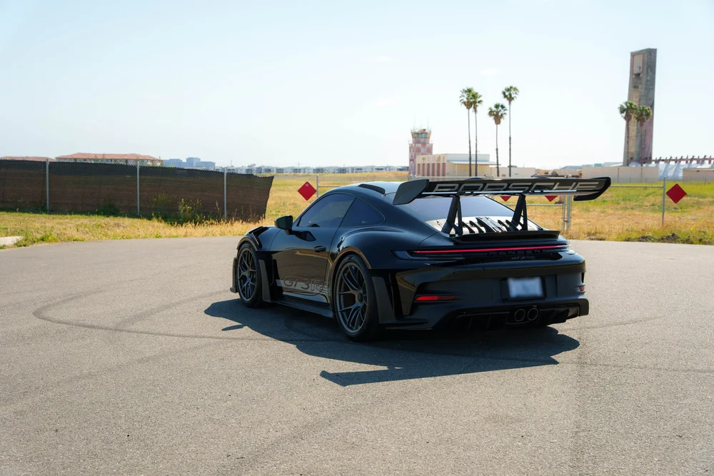Black Porsche 992.1 GT3 RS, complete opposite-side rear three-quarter with large wing