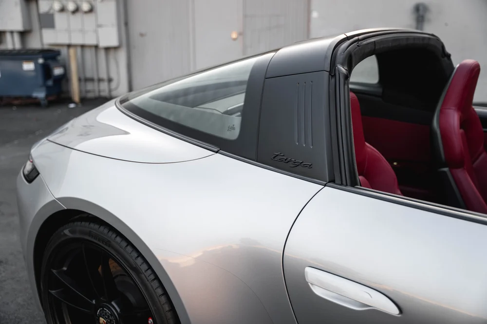 Targa bar, wraparound rear glass and silver rear-quarter panel beside the red cabin