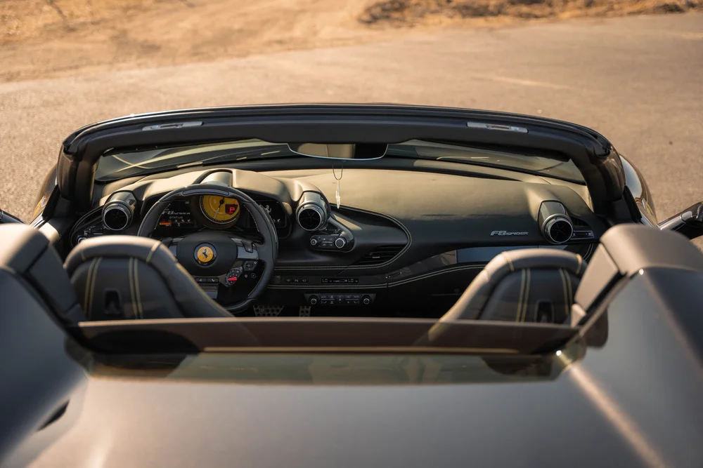 Ferrari F8 open cockpit viewed from behind with steering wheel, stitched seats, dashboard and windshield frame