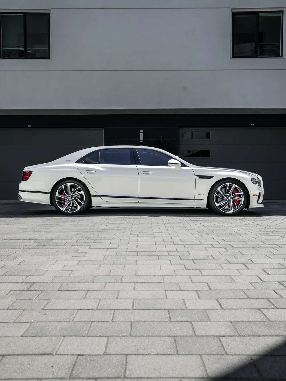 Full side profile of the white Bentley Flying Spur Speed with both wheels visible