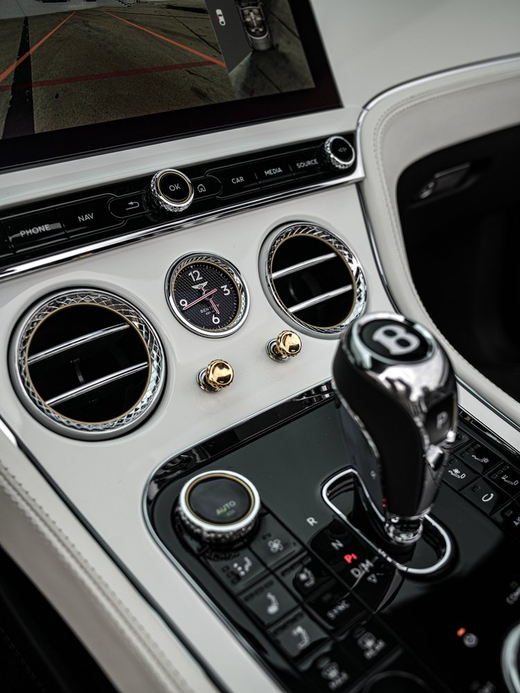 Bentley center-console clock, round air vents, gear selector and contrasting light and dark cabin trim.