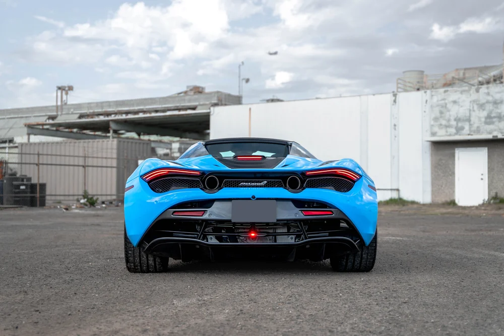 Blue McLaren 720S seen directly from the rear with two round exhaust outlets and a dark diffuser