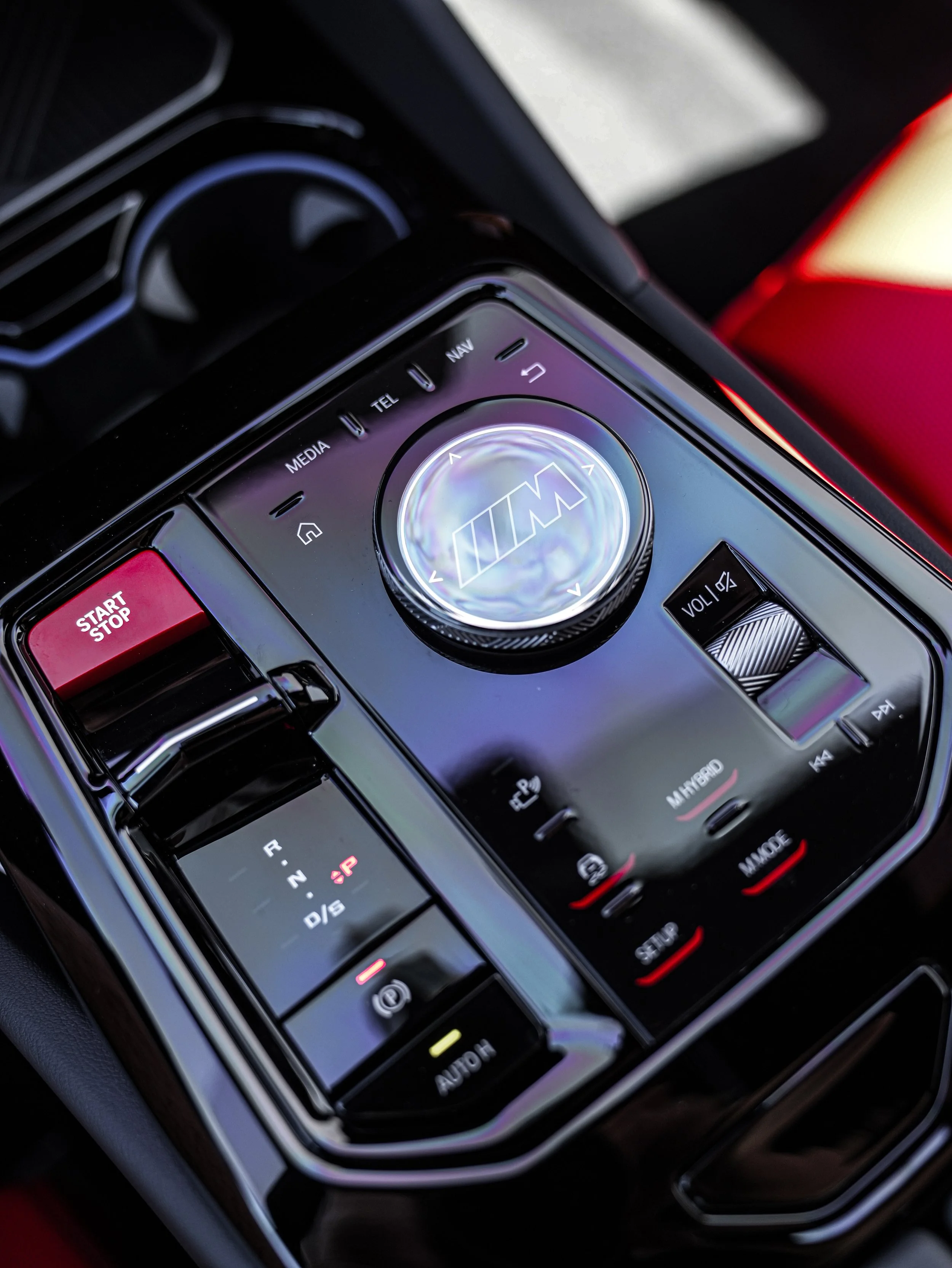 Close-up of a BMW M series car dashboard with various controls and a BMW M logo in the center.
