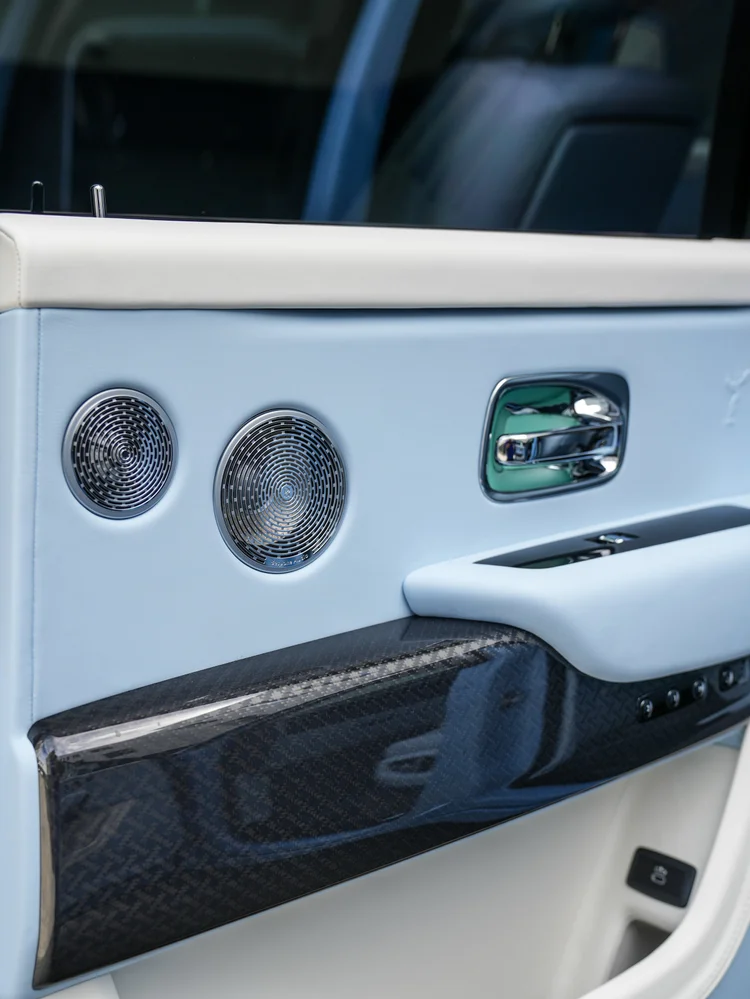 Cullinan door speakers, chrome handle and dark patterned lower trim beneath pale blue upholstery