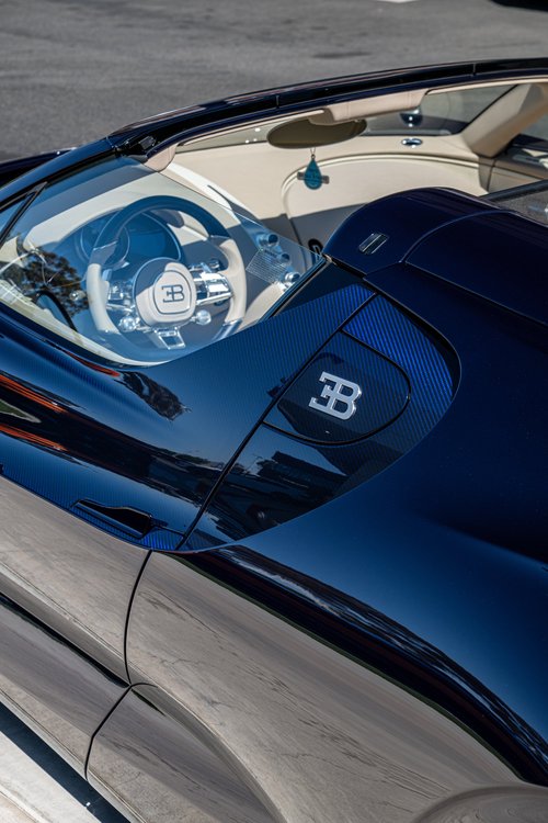 Elevated view over the W16 Mistral Blue Carbon EB emblem panel into the open cockpit and steering wheel