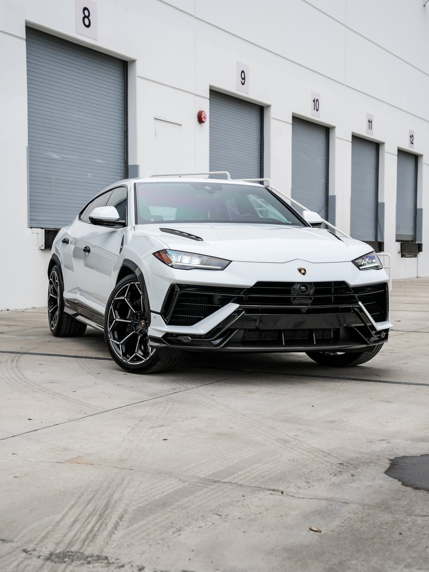 Complete front three-quarter view of the white Urus Performante with both headlamps, black front intakes, hood vents and black-and-silver wheels.