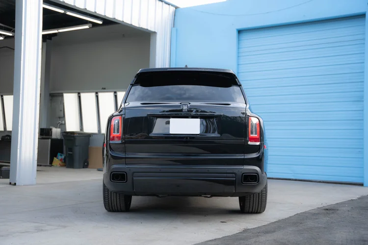 Complete rear view of the SUV parked between the open bay and blue door.