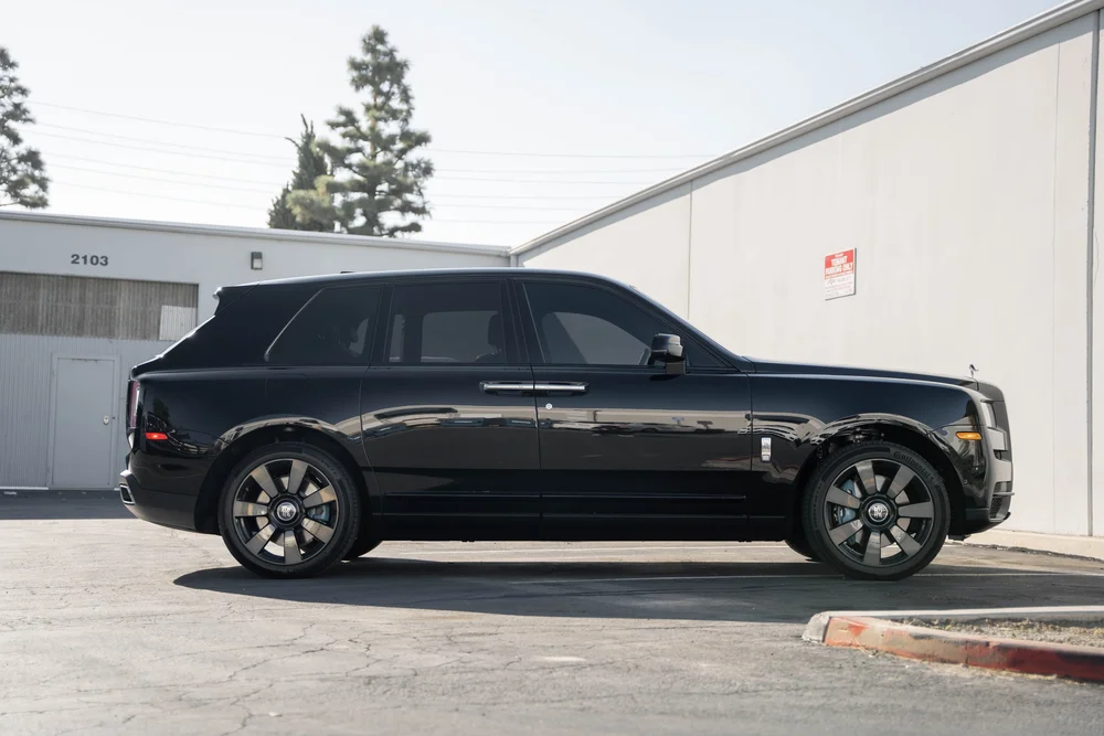 Dark Metallic Grey Rolls-Royce Cullinan — full SUV side profile with bright wheel-spoke faces and dark side glass