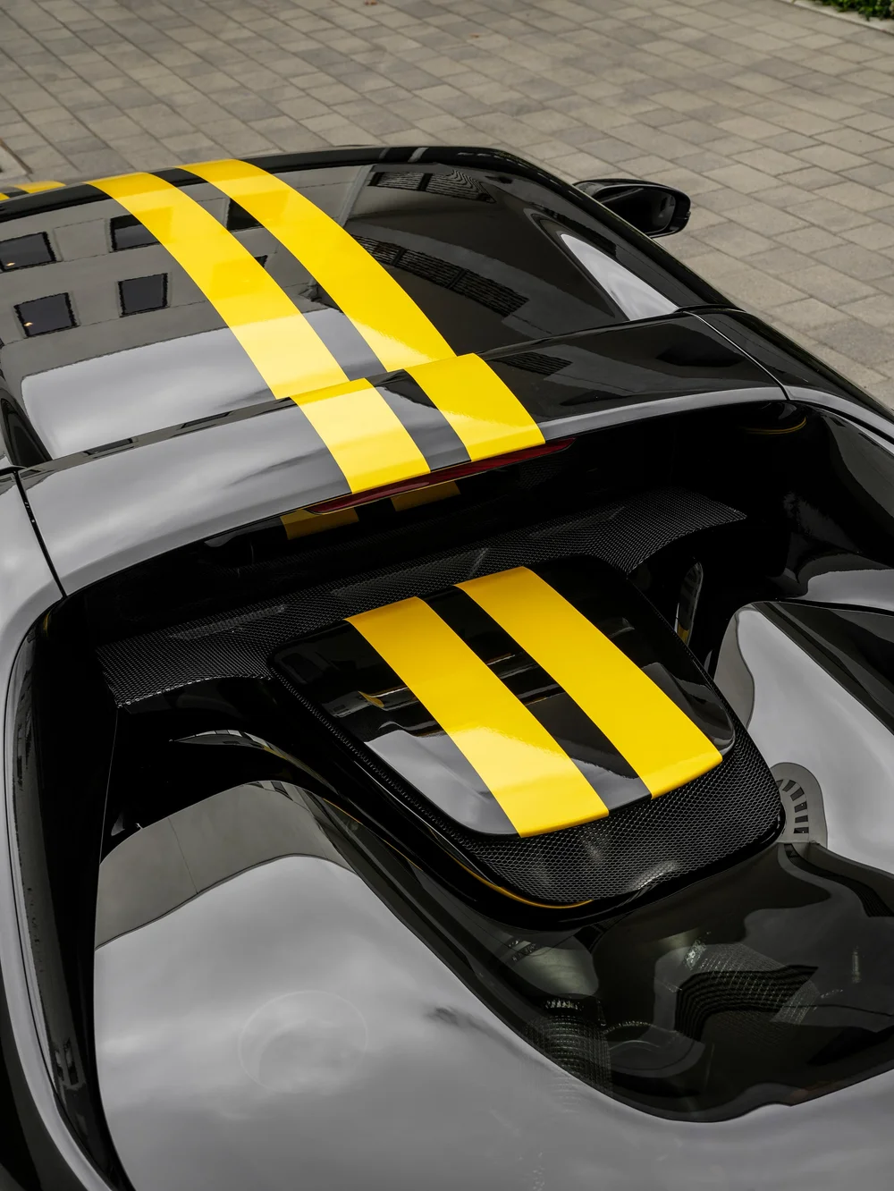 Overhead detail of the Ferrari 296 GTB roof and engine-cover area with yellow twin stripes