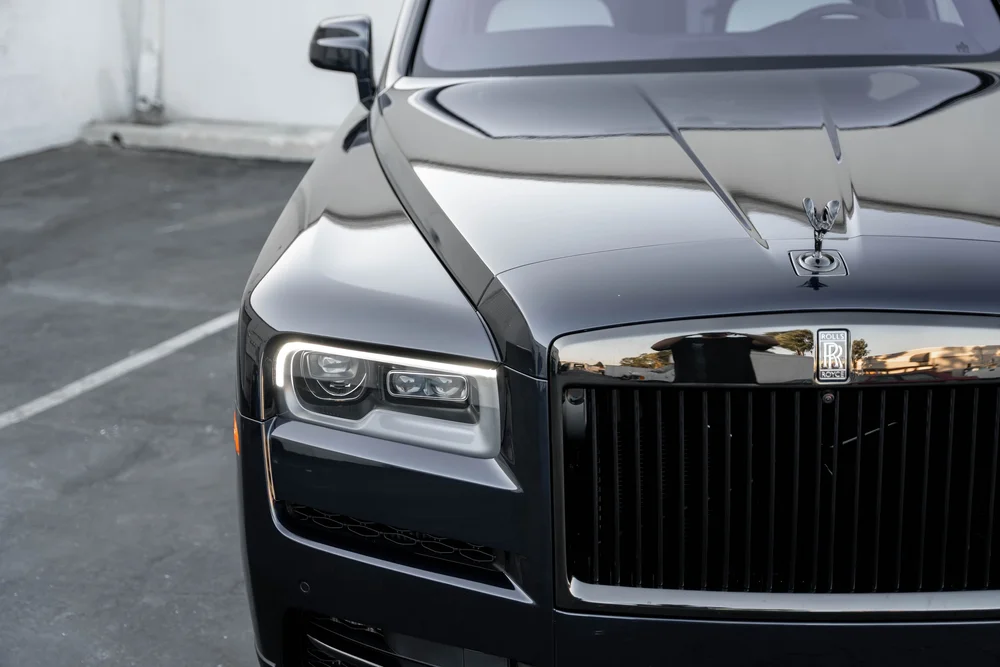 Black Rolls-Royce Cullinan Black Badge — elevated front detail showing the hood ornament, grille and headlamp area