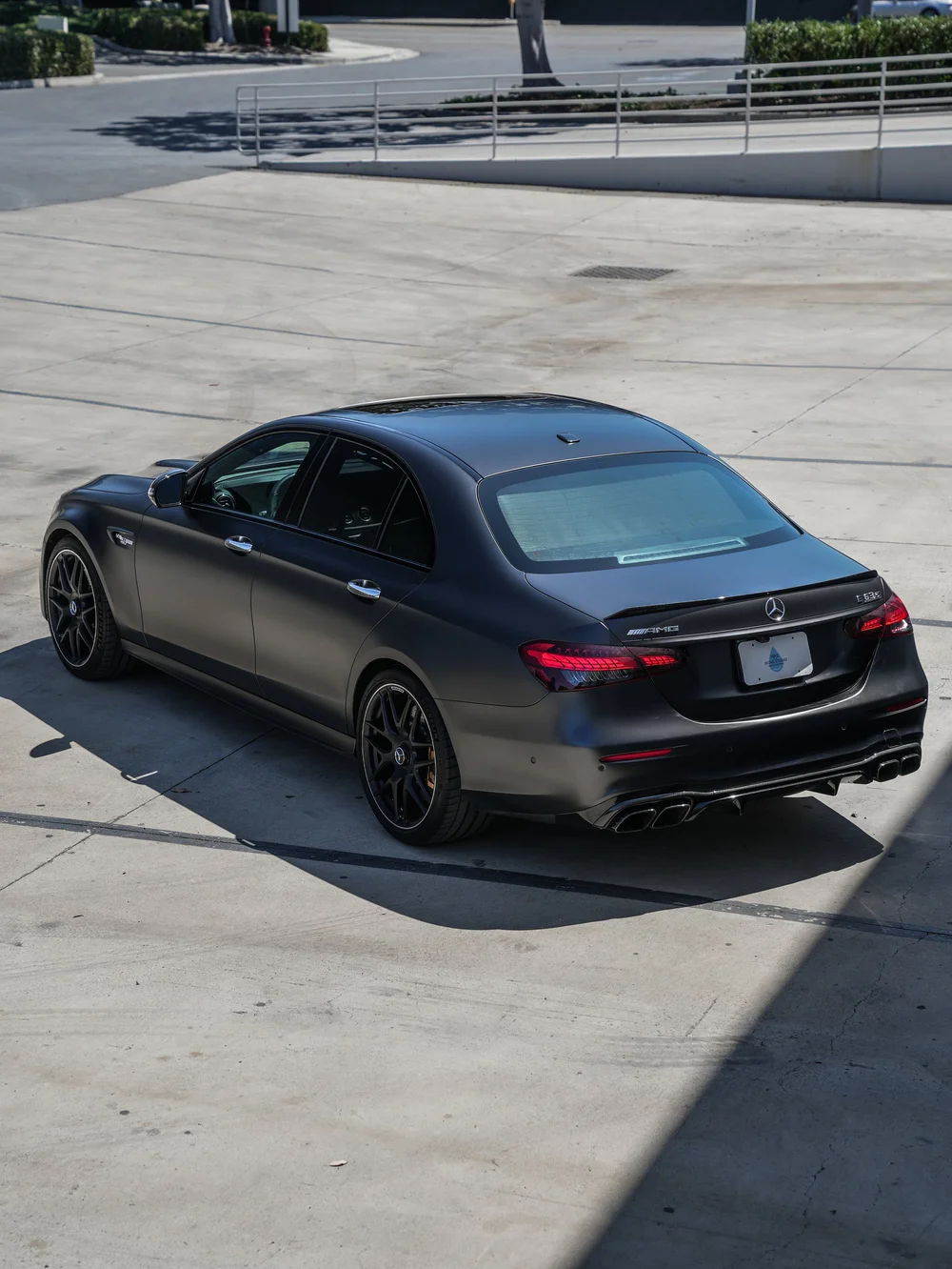 Complete elevated rear three-quarter view of the Mercedes-AMG E 63 S facing left, with red taillamps, dark wheels, yellow-gold calipers, a rear lip and four exhaust outlets.