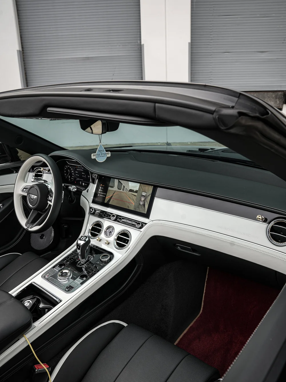 Wide Bentley Continental GTC cabin view with two-tone steering wheel, center console and Film Noir Collection dashboard lettering.