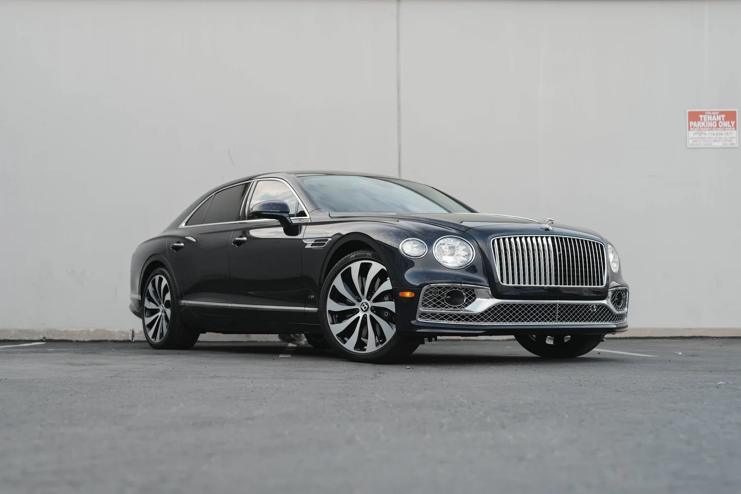 Complete front three-quarter view of the dark sedan with patterned wheels.