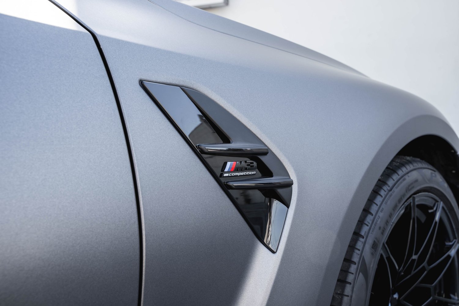 BMW M3 front-fender badge detail after silver vinyl wrap