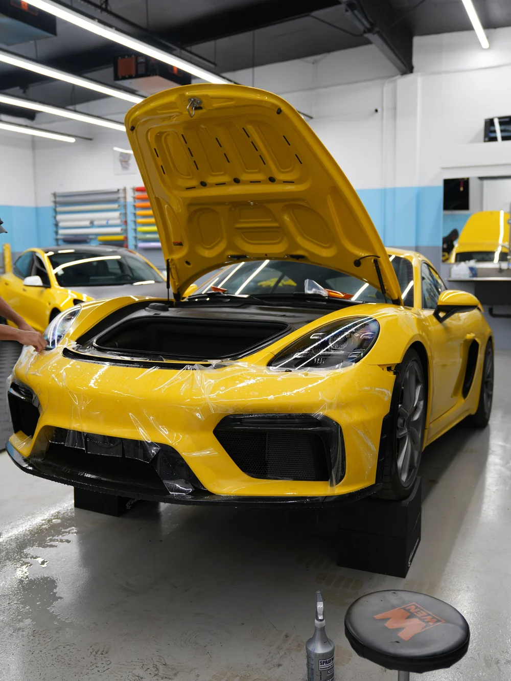 Yellow Porsche receiving front-end paint protection film inside the Toyz studio