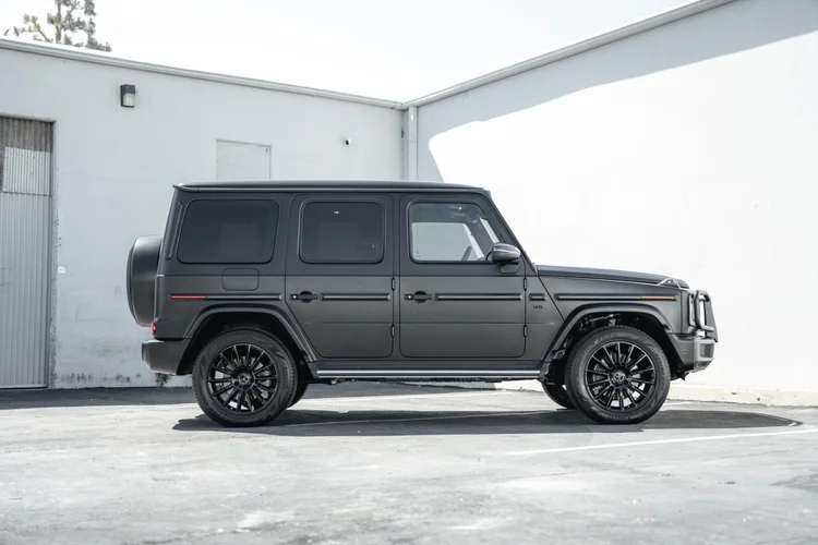 Complete side profile of the dark grey G 550 with black multispoke wheels, squared doors and a silver running board