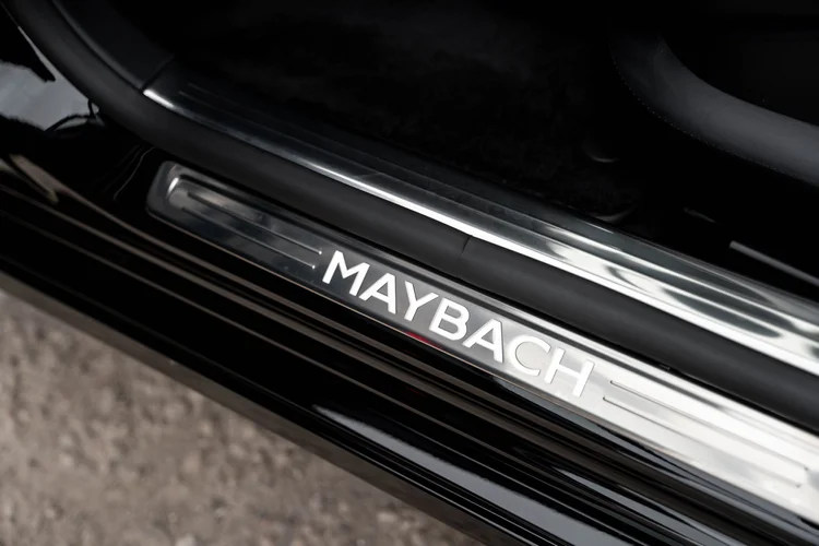 Close view of bright MAYBACH lettering on the door sill beside the dark seat edge and black floor