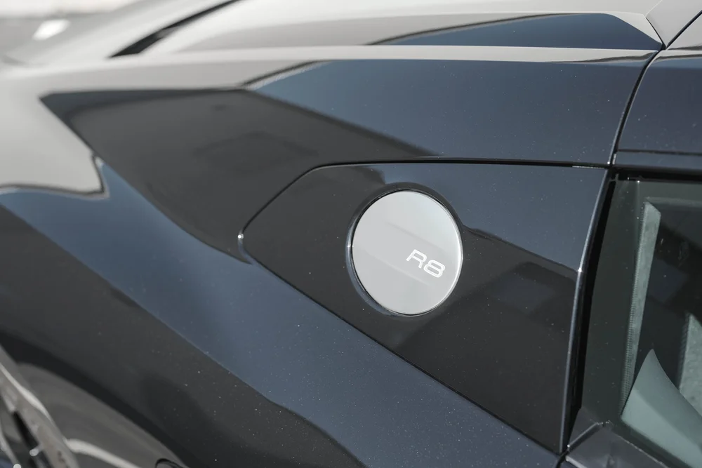 Circular R8 fuel-door cap set into the dark rear-quarter bodywork