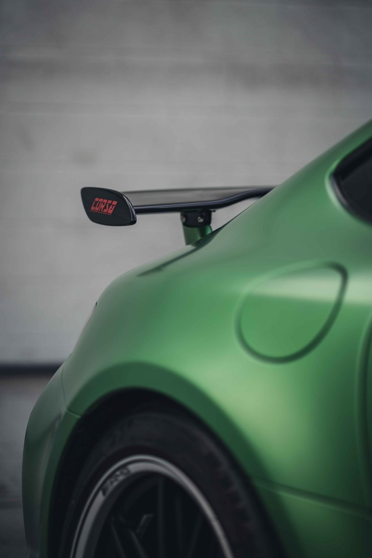 Green rear fender and fuel door over a partial dark wheel, with the black rear wing extending above.