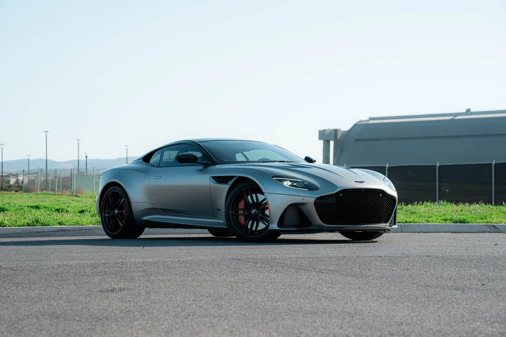 Matte-finish Aston Martin DBS in a full front three-quarter view with black wheels and red brake calipers