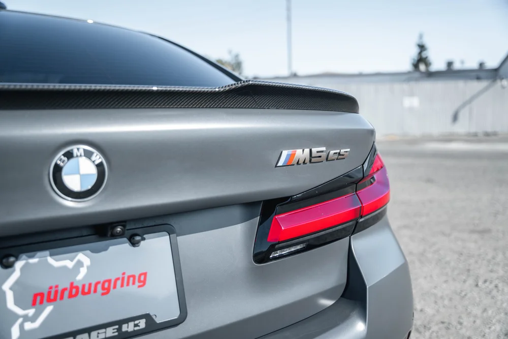 BMW M5 CS trunk badge, BMW emblem, patterned rear lip and red taillight in close view