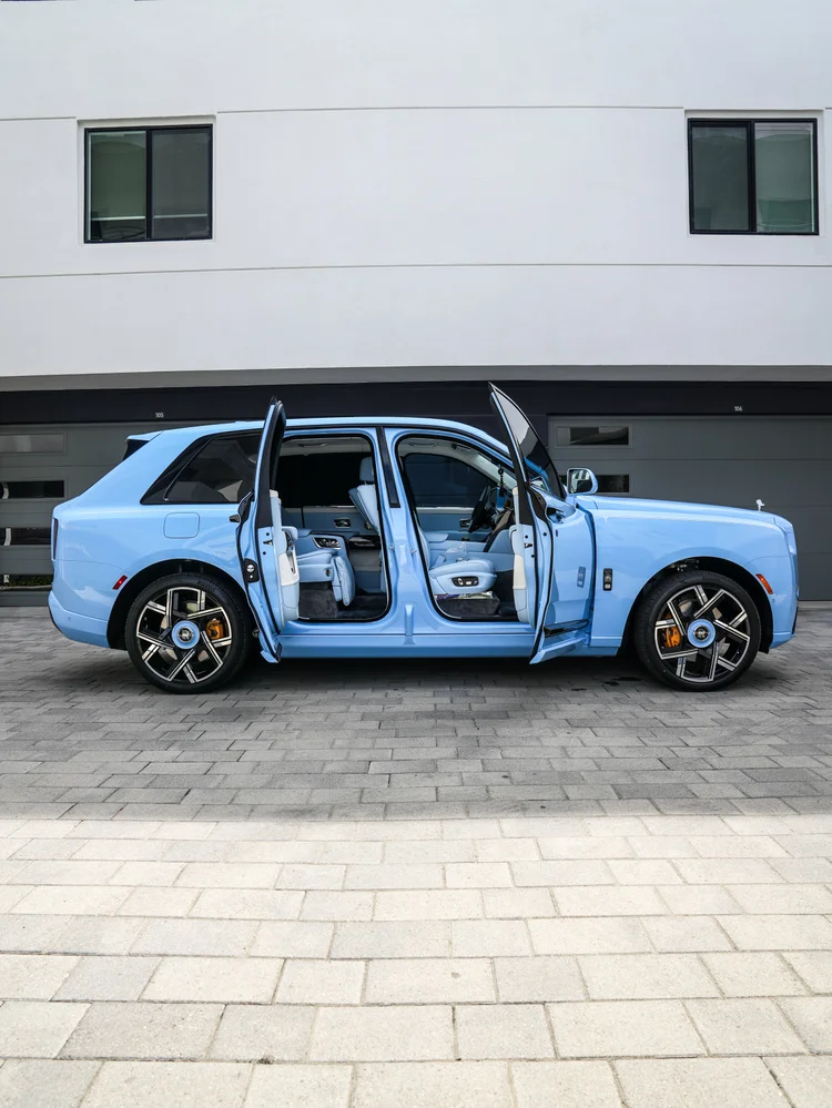 Full side view of the Powder Blue Cullinan with front and rear doors open to its pale blue cabin
