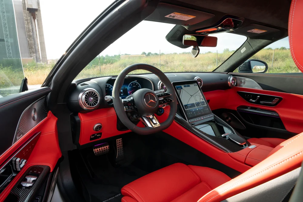 Red-and-dark SL 63 cabin with a Mercedes-star steering wheel, turbine-style vents and a tall center screen displaying a map